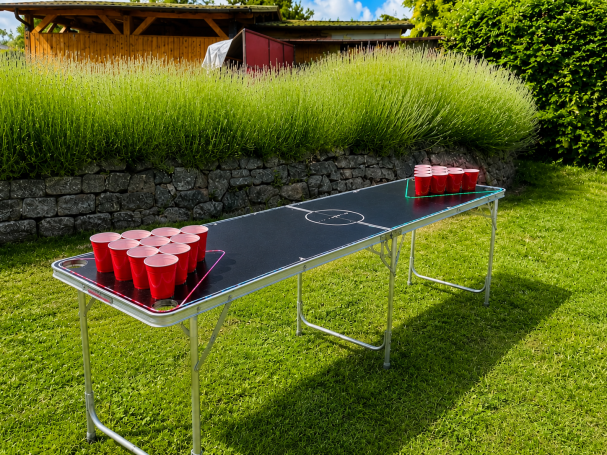 Beer Pong Tisch mieten in Aschersleben Ein Tisch mit roten Bechern für ein Beer-Pong-Spiel, auf einer grünen Wiese.